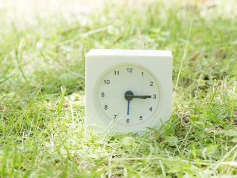 White simple clock on lawn yard,  3:15 three fifteen Stock Photos