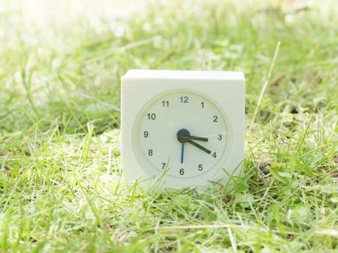 White simple clock on lawn yard, 3:20 three twenty Stock Photos