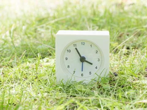 White simple clock on lawn yard, 3:55 three fifty five Stock Photos