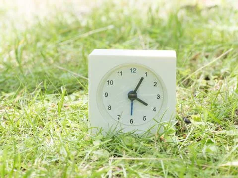 White simple clock on lawn yard, 4:05 four five Stock Photos