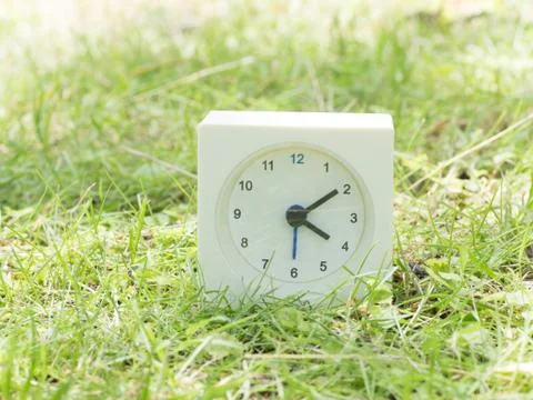 White simple clock on lawn yard, 4:10 four ten Stock Photos
