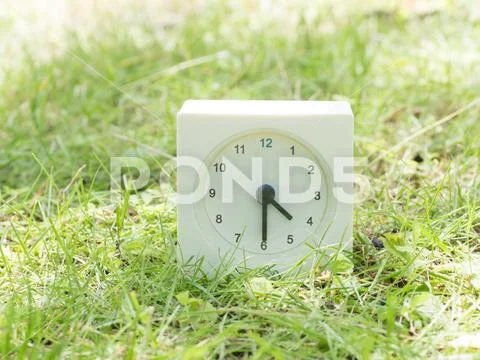 White simple clock on lawn yard, 4:30 four thirty half Stock Photos