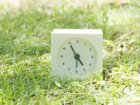 White simple clock on lawn yard, 4:55 four fifty five Stock Photos