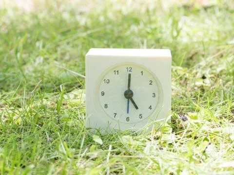 White simple clock on lawn yard, 5:00 five o'clock Stock Photos