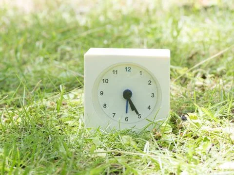 White simple clock on lawn yard, 5:25 five twenty five Stock Photos