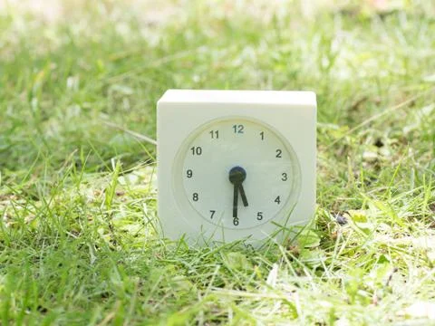 White simple clock on lawn yard, 5:30 five thirty half Stock Photos