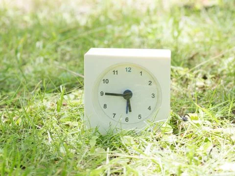 White simple clock on lawn yard, 5:45 five forty five Stock Photos