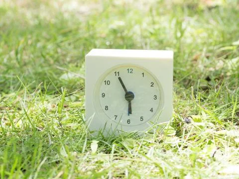 White simple clock on lawn yard, 5:55 five fifty five Stock Photos