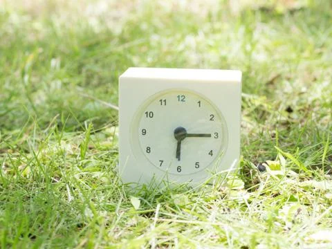 White simple clock on lawn yard, 6:15 six fifteen Stock Photos