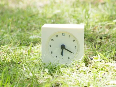 White simple clock on lawn yard, 6:20 six twenty Stock Photos