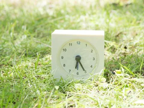White simple clock on lawn yard, 6:25 six twenty five Stock Photos