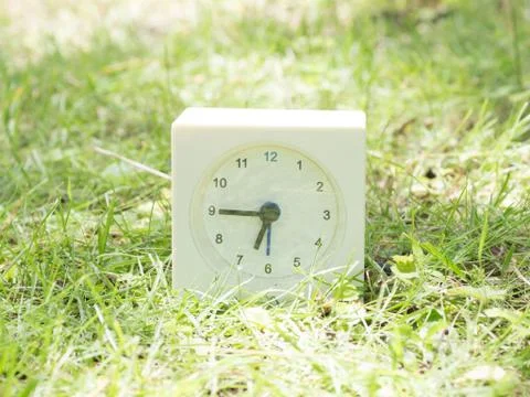 White simple clock on lawn yard, 6:45 six forty five Stock Photos