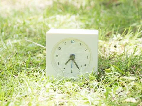 White simple clock on lawn yard, 7:25 seven twety five Stock Photos