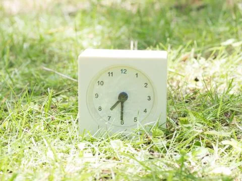 White simple clock on lawn yard, 7:30 seven thirty half Stock Photos