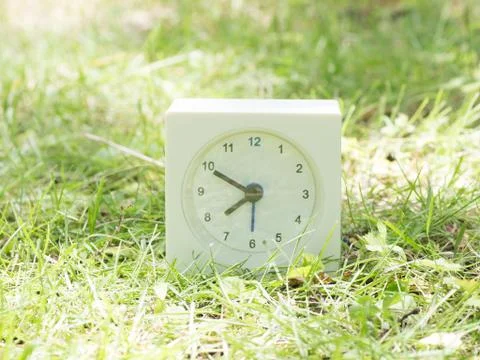 White simple clock on lawn yard, 7:50 seven fifty Stock Photos