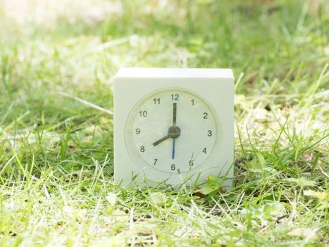 White simple clock on lawn yard, 8:00 eight o'clock Stock Photos