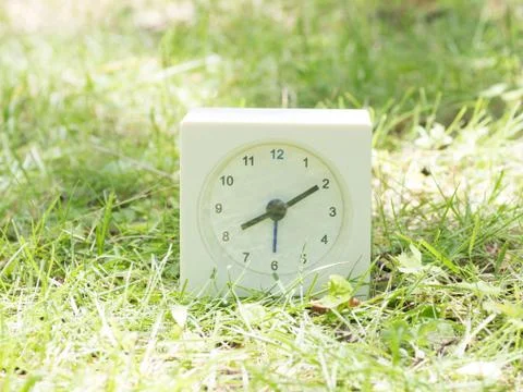 White simple clock on lawn yard, 8:10 eight ten Stock Photos