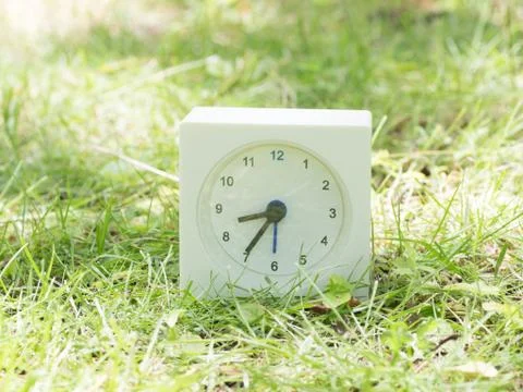 White simple clock on lawn yard, 8:35 eight thirty five Stock Photos