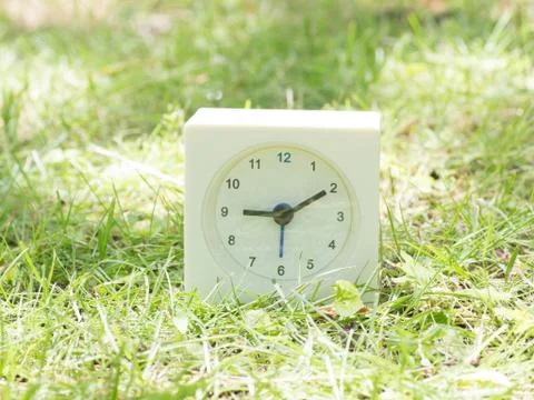 White simple clock on lawn yard, 9:10 nine ten Stock Photos