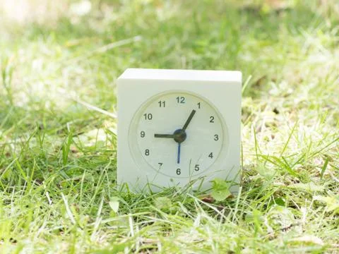 White simple clock on lawn yard, 9:05 nine five Stock Photos