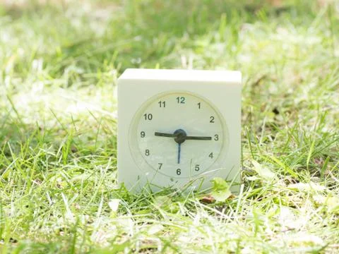 White simple clock on lawn yard, 9:15 nine fifteen Stock Photos