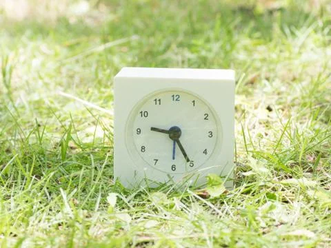 White simple clock on lawn yard, 9:25 nine twenty five Stock Photos