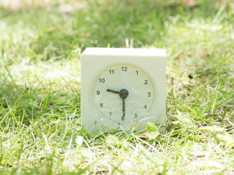 White simple clock on lawn yard, 9:30 nine thirty half Stock Photos