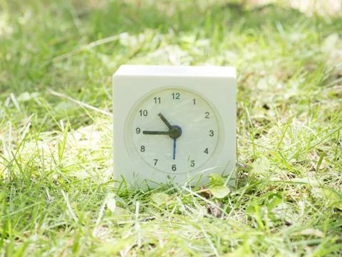 White simple clock on lawn yard, 10:45 ten forty five Stock Photos