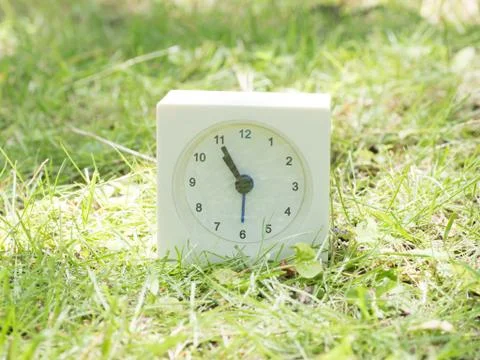 White simple clock on lawn yard, 10:55 ten fifty five Stock Photos