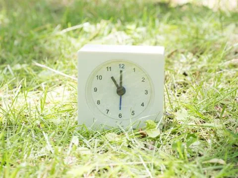 White simple clock on lawn yard, 11:00 eleven o'clock Stock Photos