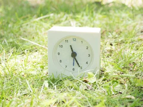 White simple clock on lawn yard, 11:25 eleven twenty five Stock Photos