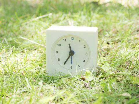 White simple clock on lawn yard, 11:35 eleven thirty five Stock Photos