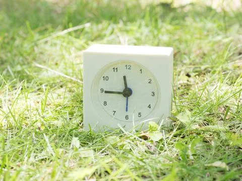 White simple clock on lawn yard, 11:45 eleven forty five Stock Photos