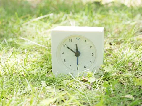 White simple clock on lawn yard, 11:50 eleven fifty Stock Photos
