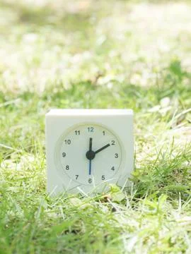 White simple clock on lawn yard, 12:10 twelve ten Stock Photos