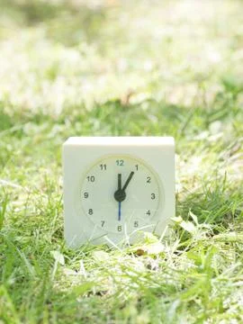 White simple clock on lawn yard, 12:05 twelve five Stock Photos