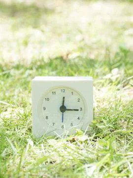 White simple clock on lawn yard, 12:15 twelve fifteen Stock Photos