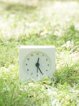 White simple clock on lawn yard, 12:25 twelve twenty five Stock Photos
