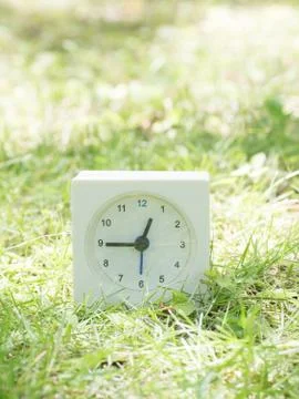 White simple clock on lawn yard, 12:45 twelve forty five Stock Photos