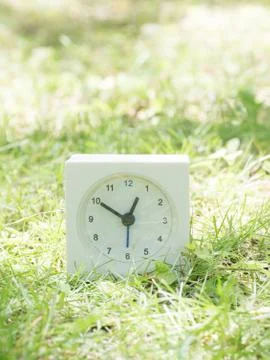 White simple clock on lawn yard, 12:50 twelve fifty Stock Photos