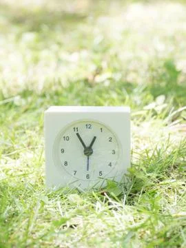 White simple clock on lawn yard, 12:55 twelve fifty five Stock Photos