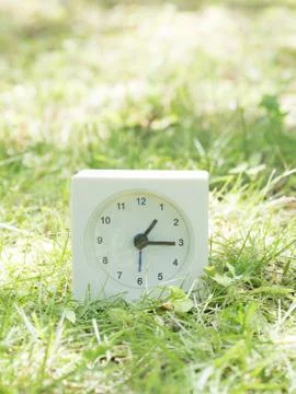 White simple clock on lawn yard, 1:15 one fifteen Stock Photos