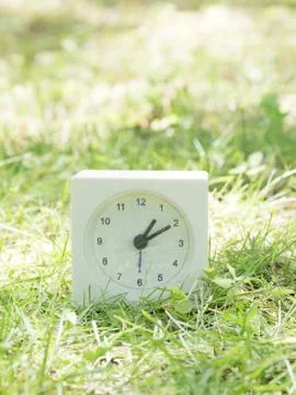 White simple clock on lawn yard, 1:10 one ten Stock Photos