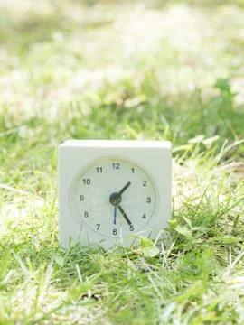 White simple clock on lawn yard, 1:25 one twenty five Stock Photos