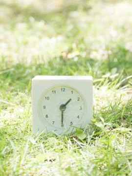 White simple clock on lawn yard, 1:30 one thirty half Stock Photos