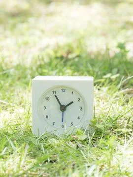 White simple clock on lawn yard, 1:55 one fifty five Stock Photos