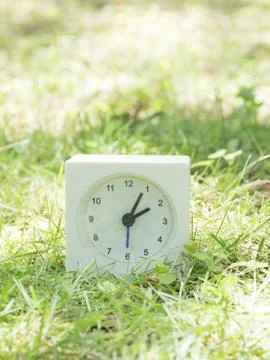 White simple clock on lawn yard, 2:05 two five Stock Photos