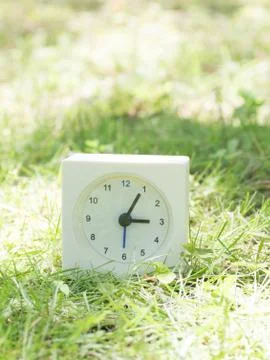 White simple clock on lawn yard, 3:05 three five Stock Photos