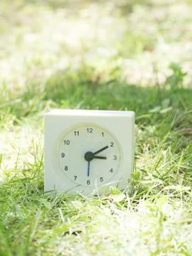White simple clock on lawn yard, 3:10 three ten Stock Photos