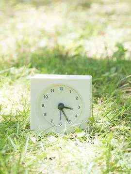 White simple clock on lawn yard, 3:25 three twenty five Stock Photos